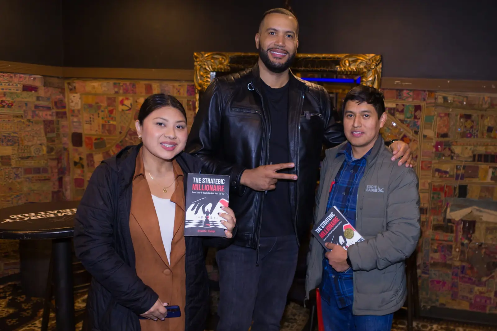 Armando Pantoja with two attendees holding his book at a previous event