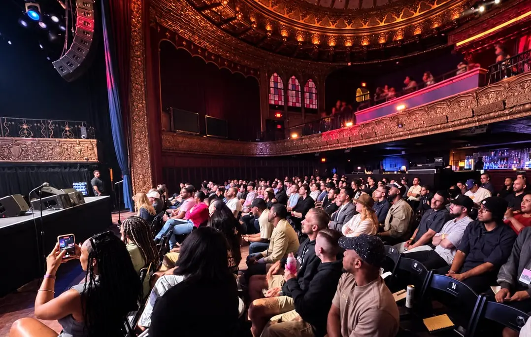 A full ornate theatre watching the stage at a previous event